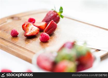 fruits, berries, diet, eco food and objects concept - close up of fresh ripe red strawberries on cutting board