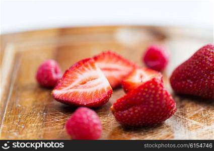 fruits, berries, diet, eco food and objects concept - close up of fresh ripe red strawberries on cutting board