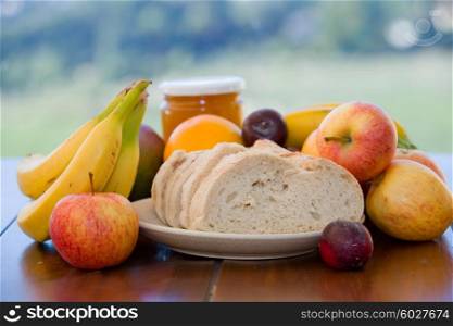 fruits, bread and honey, on table in the garden