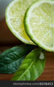 fruits, citrus, detox, diet and objects concept - lime slices on wooden table