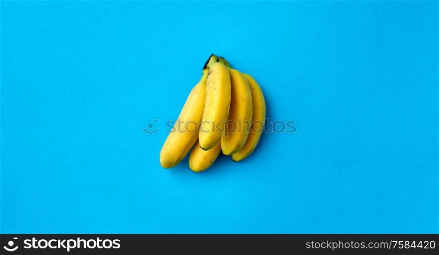 fruits, diet and food concept - close up of ripe banana bunch on blue background. close up of ripe banana bunch on blue background