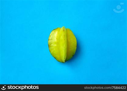 fruits, diet and food concept - close up of ripe carambola or star fruit on blue background. ripe carambola or star fruit on blue background