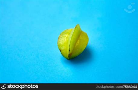 fruits, diet and food concept - close up of ripe carambola or star fruit on blue background. ripe carambola or star fruit on blue background