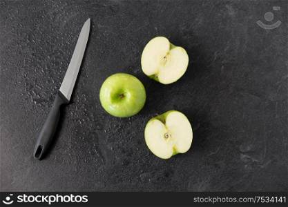 fruits, diet, eco food and objects concept - green apples and kitchen knife on slate stone background. green apples and kitchen knife on slate background