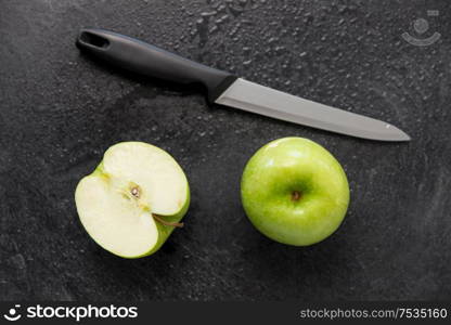 fruits, diet, eco food and objects concept - green apples and kitchen knife on slate stone background. green apples and kitchen knife on slate background