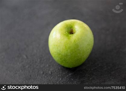 fruits, diet, eco food and objects concept - ripe green apple on slate stone background. ripe green apple on slate stone background