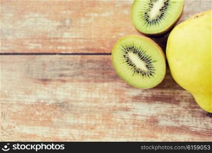 fruits, diet, food and objects concept - close up of ripe kiwi and pear on table