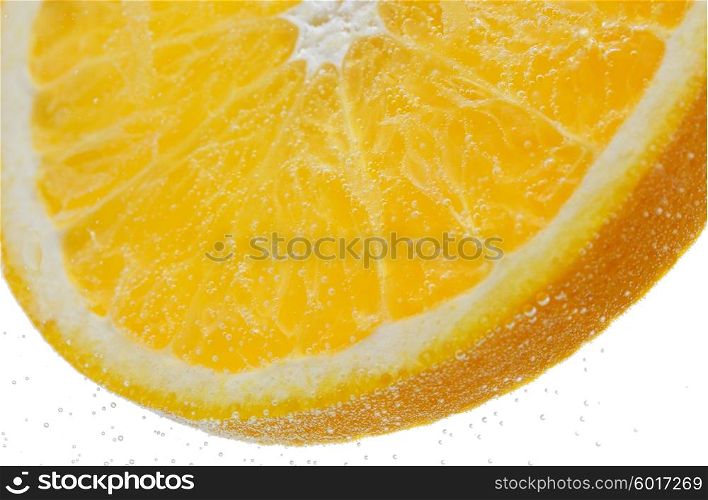 fruits, food and healthy eating concept - close up of slice of fresh orange falling or dipping in water with splash over white background