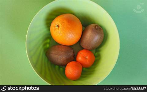 fruits in plastic bowl. many fruits in plastic bowl, including orange, kiwi and tangerine