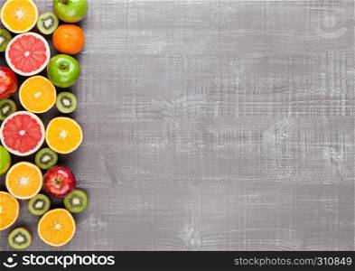 Fruits mix grapefruit orange apples kiwi on wooden background
