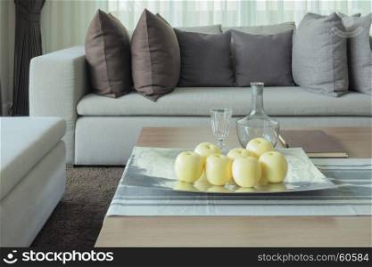 fruits on wooden table in modern living room design with sofa and pillows