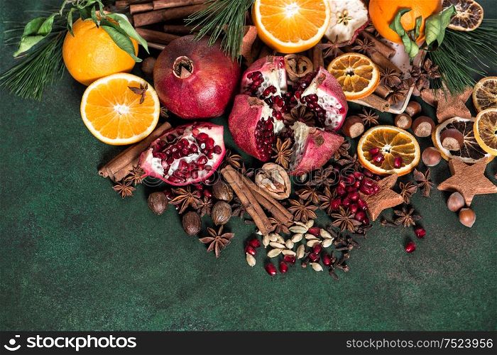 Fruits pomegranate and orange with spices and ingredients cinnamon, star anise, cardamon, nutmeg on rustic stone background