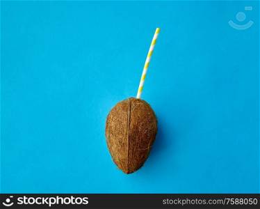 fruits, summer and food concept - coconut drink with paper straw on blue background. coconut drink with paper straw on blue background