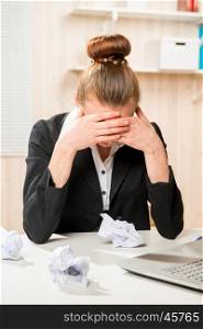 Frustrated business woman with crumpled paper on the desk thinking