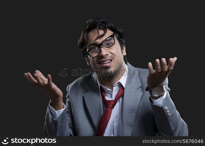 Frustrated businessman gesturing against black background