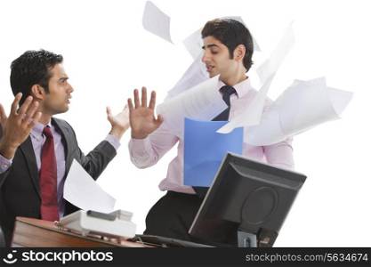 Frustrated businessman throwing papers on male executive