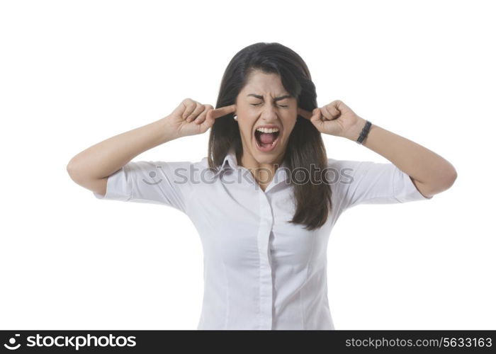 Frustrated businesswoman with fingers in ears shouting over white background