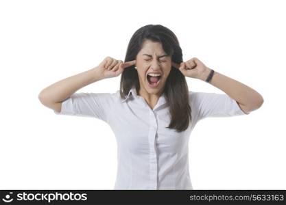 Frustrated businesswoman with fingers in ears shouting over white background
