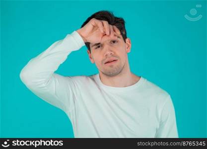 Frustrated european man over teal wall background. Guy is tired, bored of work or studying, he disappointed, helpless. High quality photo. Frustrated european man over teal wall background. Guy is tired, bored of work or studying, he disappointed, helpless