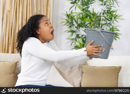 frustrated female client holding pot while water leaking from roof