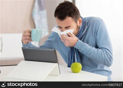 frustrated handsome young man sneezing at home