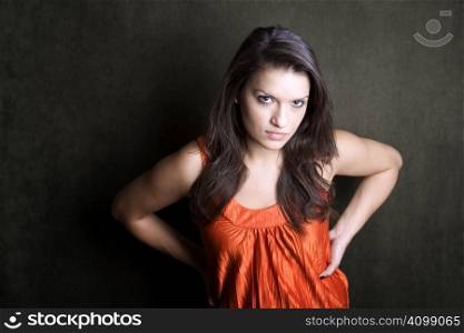 Frustrated Hispanic woman in orange on green background