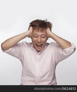 Frustrated man with hands on head and mouth open, studio shot