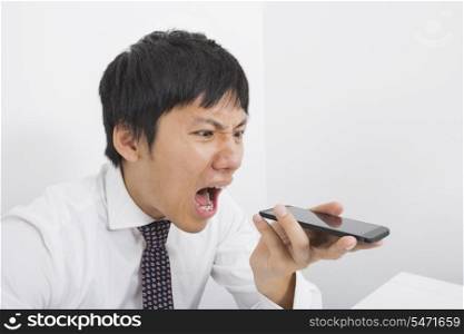Frustrated mid adult businessman screaming on cell phone in office