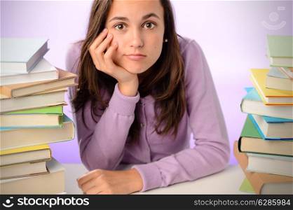 Frustrated student girl sitting between stacks of books purple background