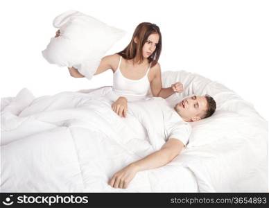 Frustrated wife trying to stop husband from snoring with pillow in bed, isolated.