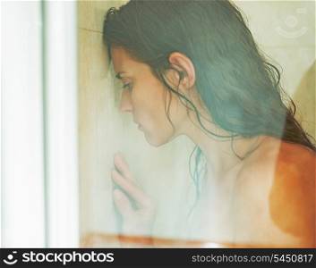 Frustrated woman leaning on weeping glass shower door