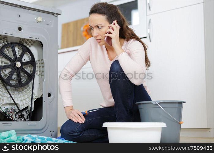 frustrated woman on the phone next to washing machine
