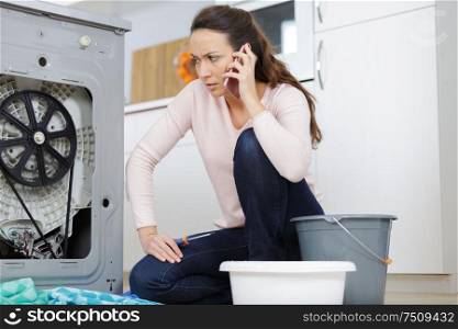 frustrated woman on the phone next to washing machine