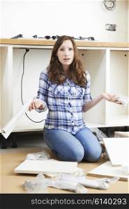 Frustrated Woman With Self Assembly Furniture In Kitchen
