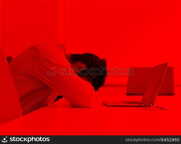 Frustrated young business man have stress problems. Sitting alone at office meeting room and working on laptop compute.