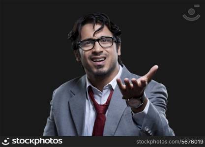 Frustrated young businessman gesturing over black background