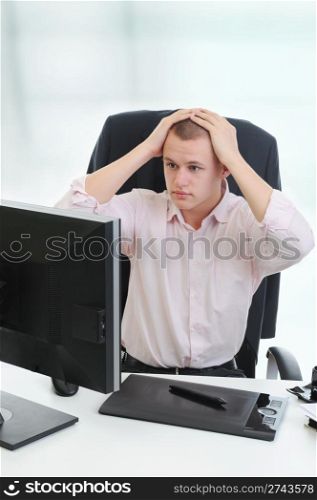 Frustrated young businessman in front of computer.