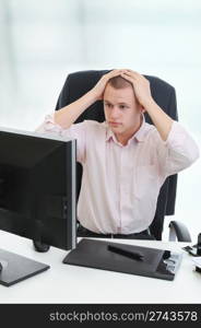 Frustrated young businessman in front of computer.