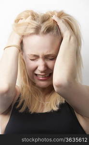 Frustrated young Caucasian woman with hands in hair against white background