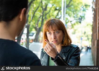 Frustrated young couple having argument and quarrelling with each other outdoors in the street. Relationship problems.