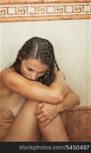 Frustrated young woman sitting in shower