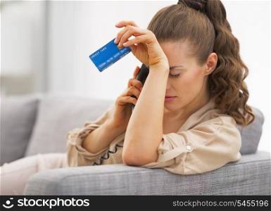 Frustrated young woman with credit card and talking phone