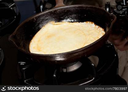 Frying pan on gas stove with pancake mixture being cooked