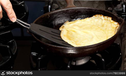 Frying pan on gas stove with pancake mixture being cooked