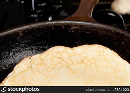 Frying pan on gas stove with pancake mixture being cooked