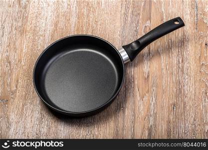 Frying pan on wooden table background.