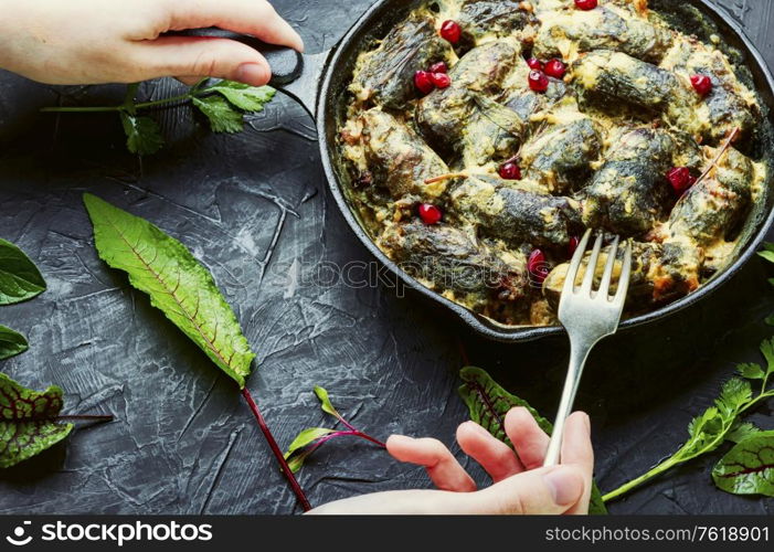 Frying pan with cooked oriental dolma in hands.Appetizing oriental food.Dolma in grape leaves.. Eastern dolma or sarma