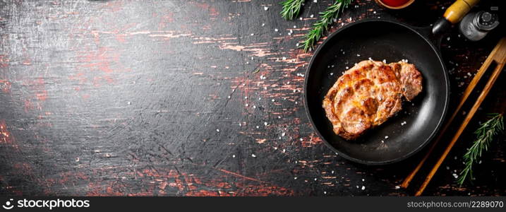 Frying pan with grilled steak. Against a dark background. High quality photo. Frying pan with grilled steak.