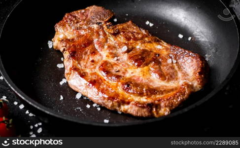 Frying pan with grilled steak. Against a dark background. High quality photo. Frying pan with grilled steak.