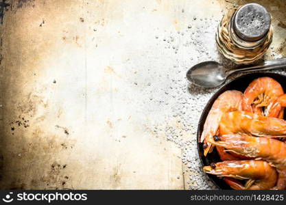 Frying pan with shrimp and salt. On an old rustic background .. Frying pan with shrimp and salt.